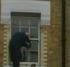 Man on window ledge fixing something