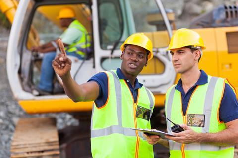 Black construction worker talks to a white colleague 