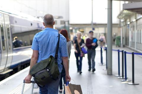 Passengers with luggage walking along train platform