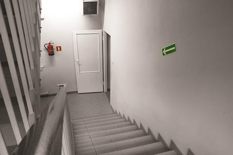 A clearly signposted open door at the bottom of a flight of stairs with a fire extinguisher next to it