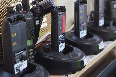 Several two way radios sitting on a shelf